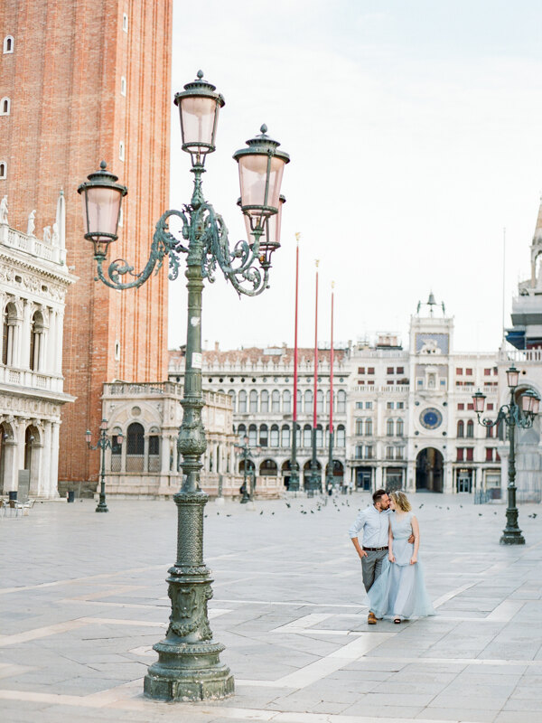 Couple photoshoot in Italy: a couple in love walks along the empty square of San Marco in Venice