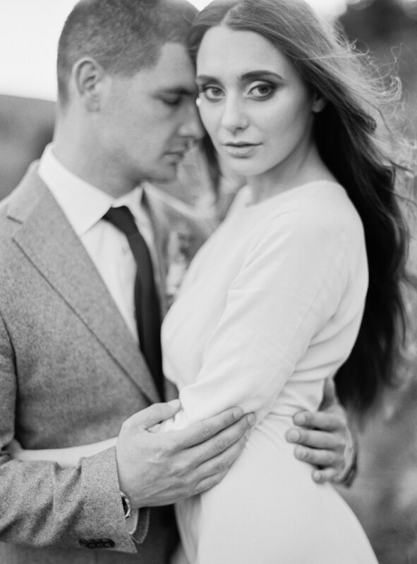 Wedding photography portfolio in Italy: Portrait of a couple where the guy gently hugs a girl who has big deep eyes and long luxurious hair that the wind develops