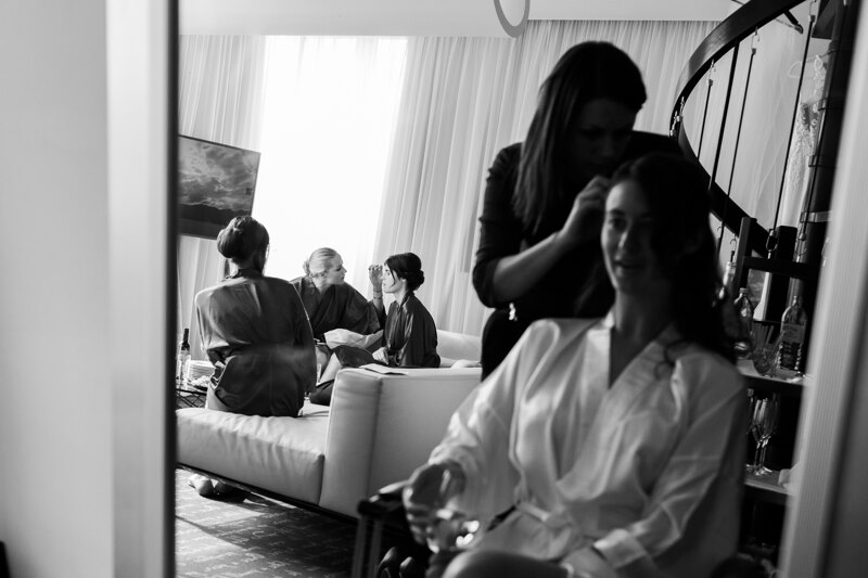 Wedding photography portfolio in Italy: The morning of the bride with her friends, in the hotel room, where preparations are being made for the wedding, the bride is doing her hair, and the girls are makeup
