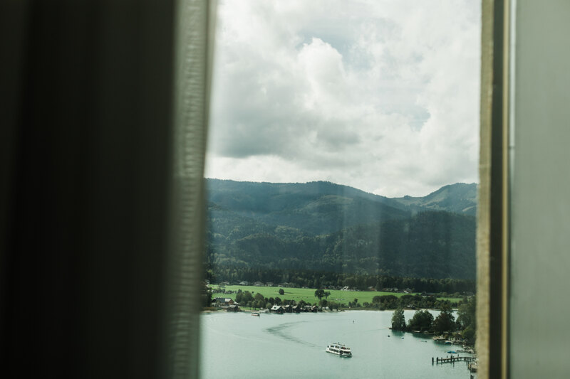 Wedding photography portfolio in Italy: The view from the hotel room on the mountains and the mountain lake on which the boat floats