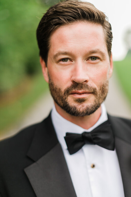 Wedding photography portfolio in Italy: Portrait of a groom, with a neat haircut and beard, in a black tuxedo