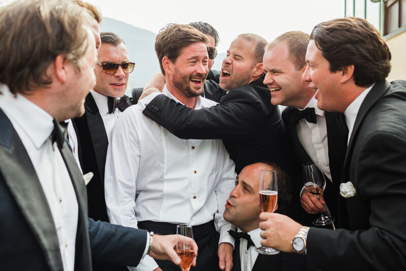 Wedding photography portfolio in Italy: Groom with his friends cuddling and drinking champagne on the hotel terrace