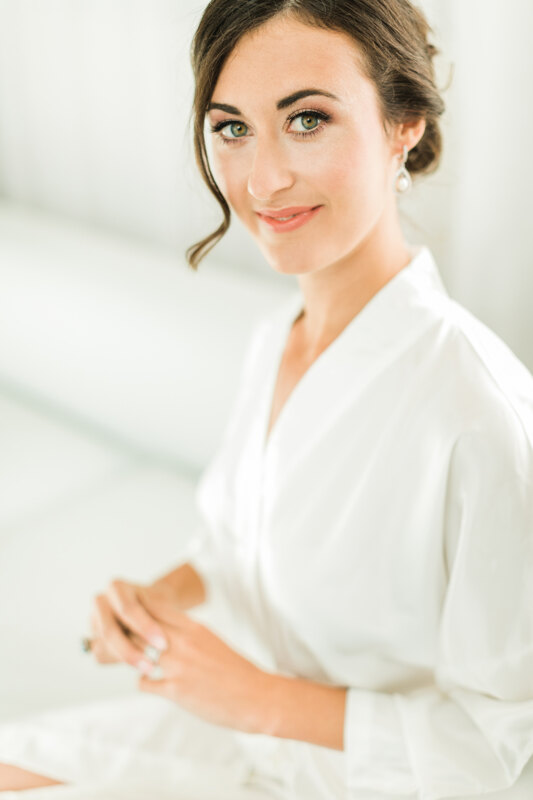 Wedding photography portfolio in Italy: Portrait of a bride in a white dressing gown with a hairstyle and makeup, which is preparing for the ceremony