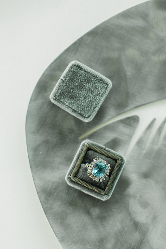 Wedding photography portfolio in Italy: Vintage ring in a velvet box, in a frame of white gold, the center of which is decorated with an unusual transparent blue stone, decorated with diamonds on the edge
