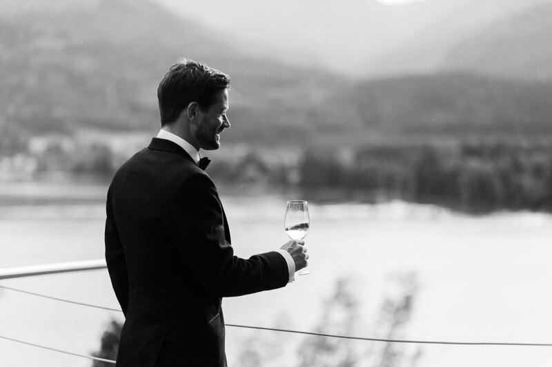 Wedding photography portfolio in Italy: The groom stands on the veranda of the hotel with a glass of wine in his hand