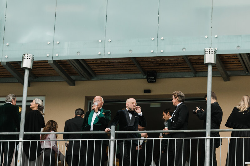  Wedding photography portfolio in Italy: Reputable guests smoke cigarettes and drink on the hotel balcony