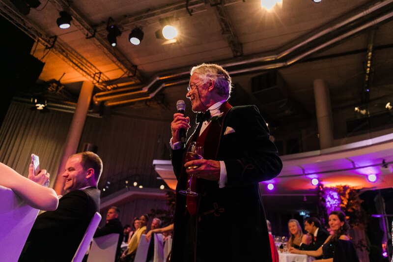 Wedding photography portfolio in Italy: Senior man with a microphone and a glass of champagne in his hands, says a toast