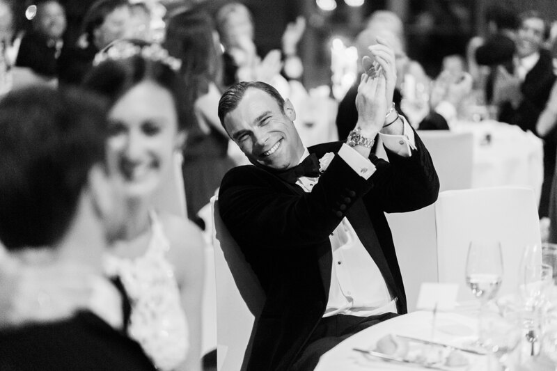 Wedding photography portfolio in Italy: A man in a tuxedo applauds while sitting at the table
